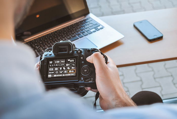 A photographer adjusting camera settings on a Canon DSLR