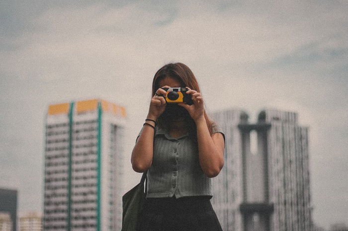 Young woman holding a Kodak disposable camera to her face