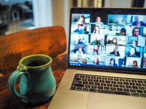 Cup of coffee next to a Mac laptop with a conference call in progress