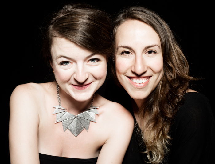 A studio portrait of two girls against a black backdrop