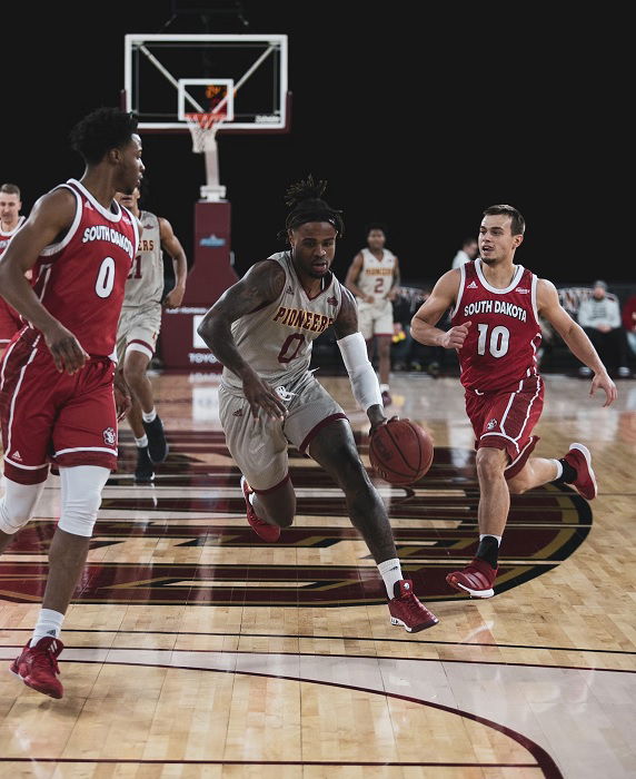 Basketball player running through opposition players with the ball on a basketball court