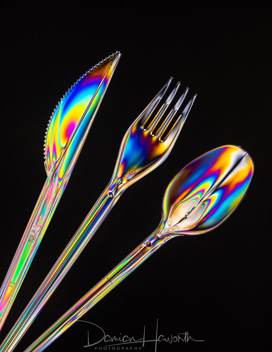 Iridescent stainless steel cutlery against a black background.