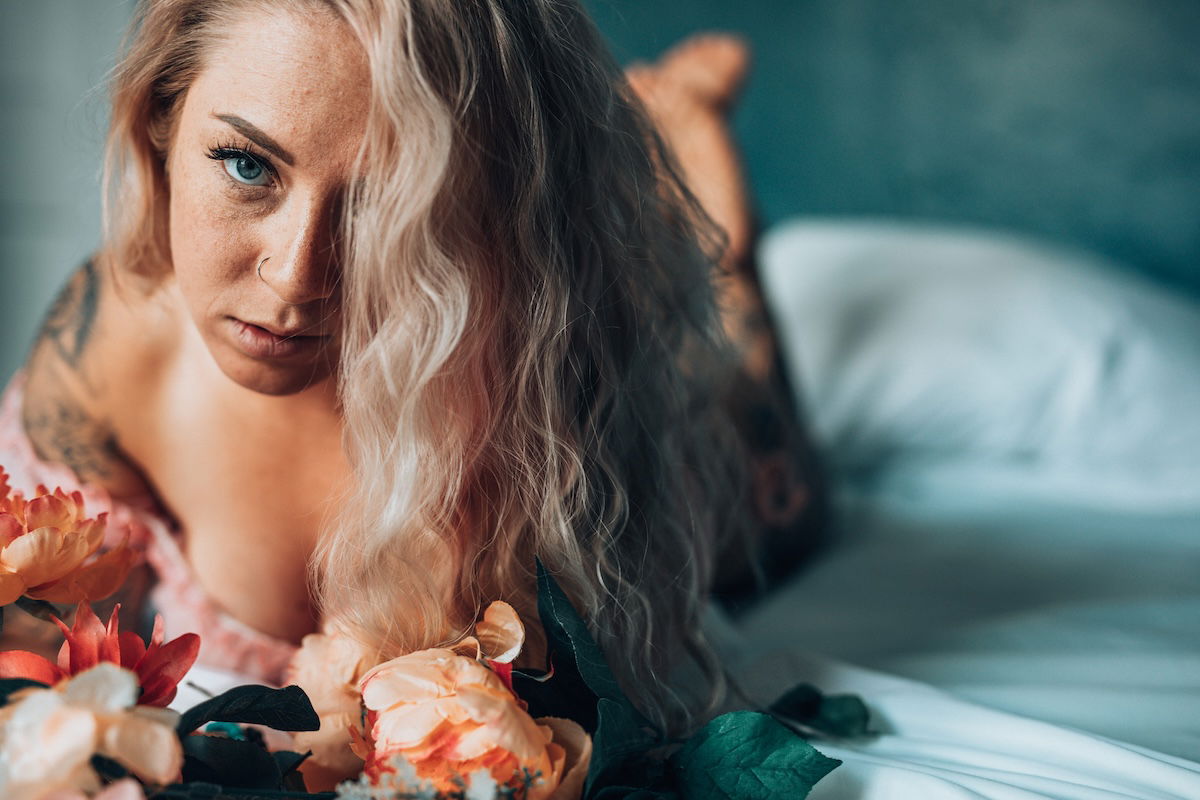 Women lying in bed with flowers for a boudoir photoshoot