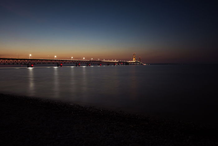 a dramatic photo of a bridge over a river at sunset, utilizing dynamic range in photography 