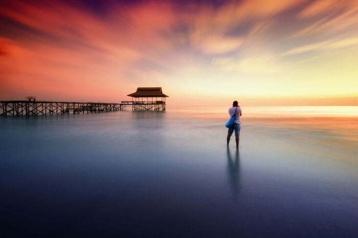 Long exposure photo of a photographer on a beach at evening time