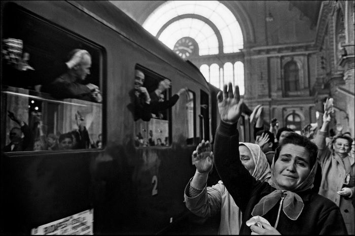 People on platform waving goodbye to train travelers