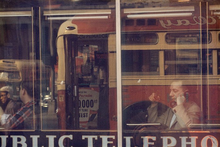 Man seen through window with bus reflected