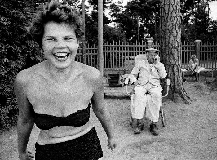 Woman in bikini laughing with old man sitting behind