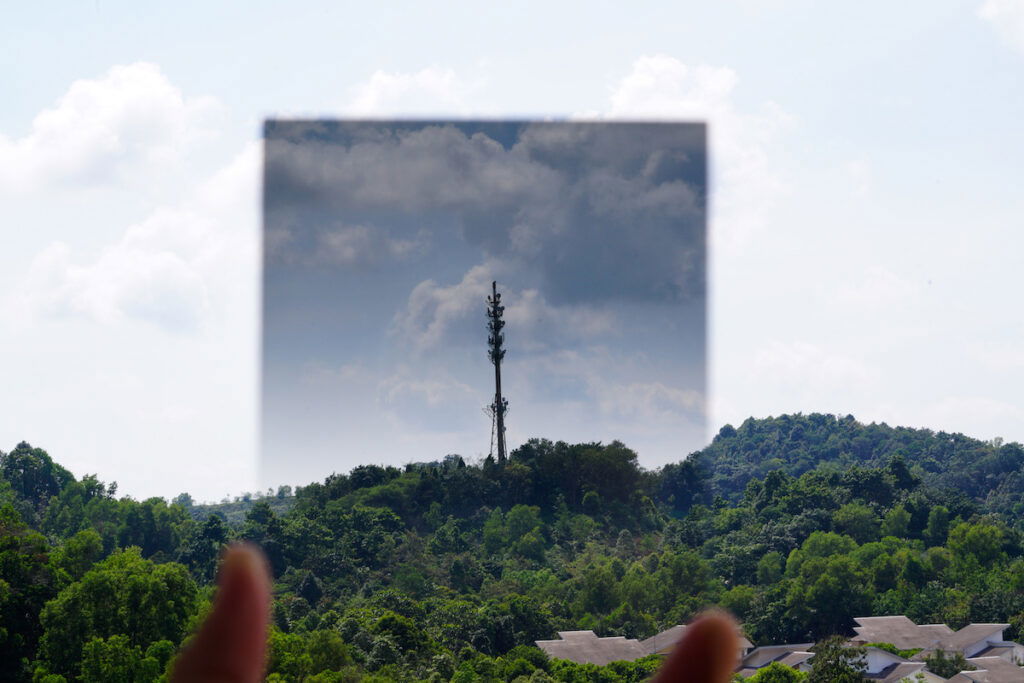 A graduated ND filter being held up to a sky and landscape