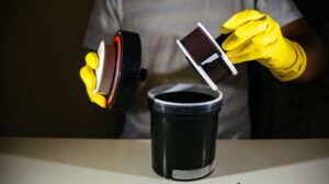 an image of a man in yellow gloves using a film development tank