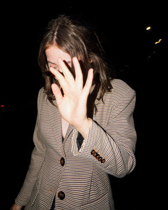 A girl holding her hand up to the camera against a dark background, hoe to take good photos