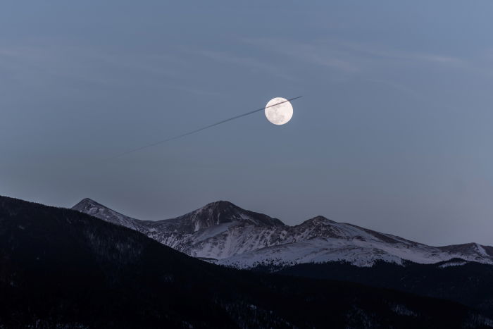 A full moon in a sky above mountains