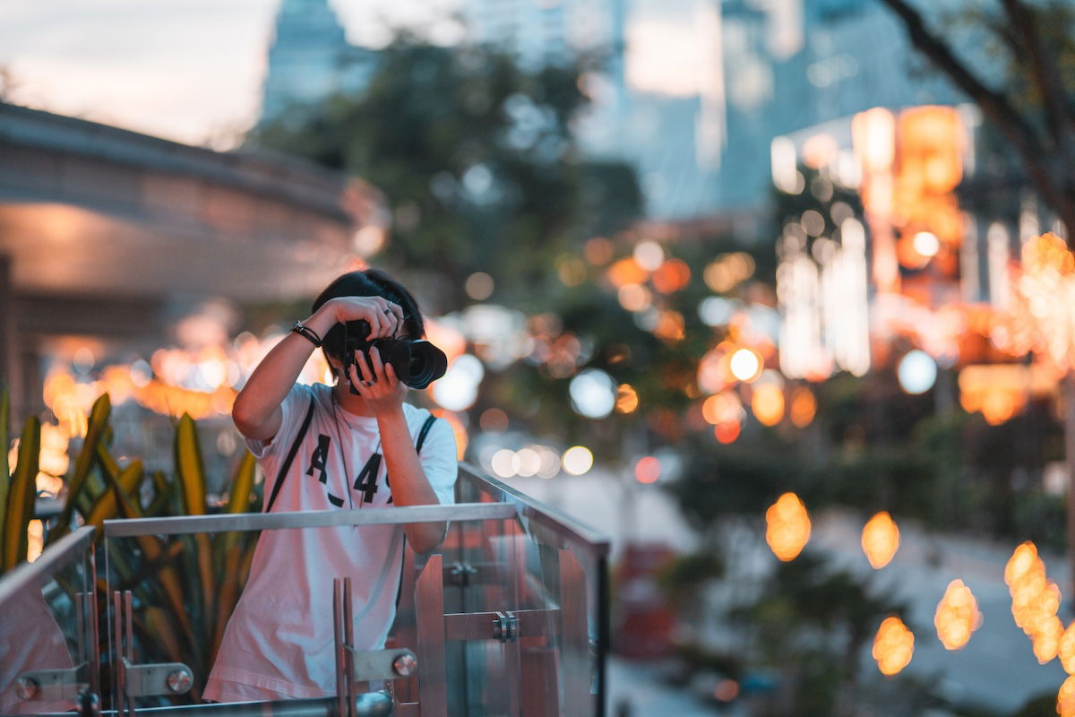 A photographer shooting photos from a city balcony with light bokeh in the background