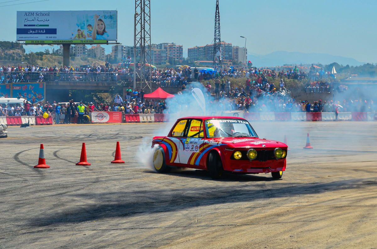 A rally car racing with smoke coming from its wheels as an example for sports photography