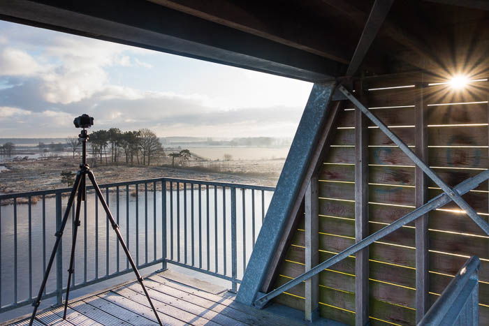 artistic sunrise photo of camera tripod overlooking a marsh field in Belgium